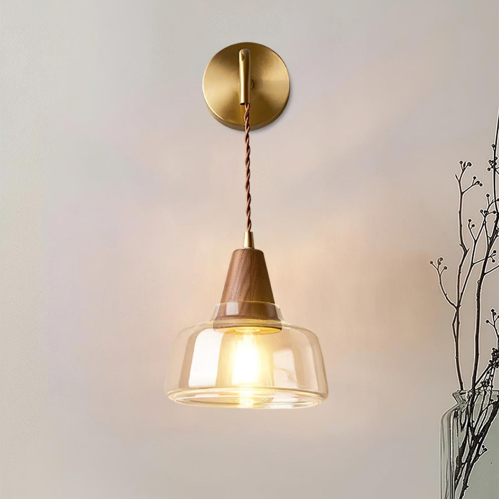 Clérachic bell sconce lit beside a glass vase of dried branches on a soft gray bedroom wall.