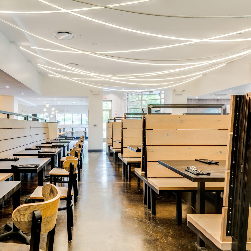 Many fine Clérachic LED rope pendants layered across a restaurant ceiling above dark tables and pale wooden booths.