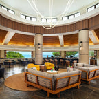 Clérachic LED rope pendants hanging from a round dome above a round lounge with wood-framed sofas and yellow chairs.