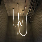Clérachic LED rope pendants hanging in tangled, looping lines against a dark tiled wall, seen from below.