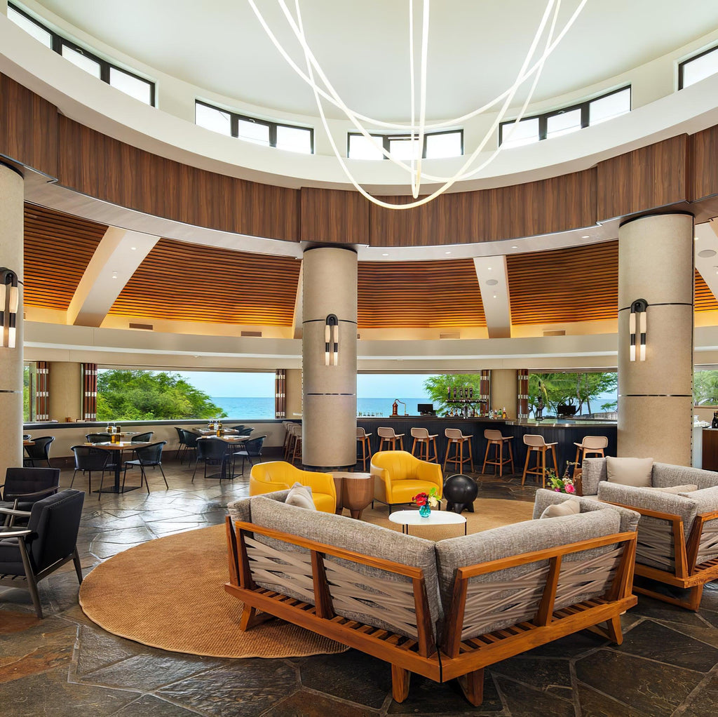 Clérachic LED rope pendants hanging high over a round lounge with wood-framed sofas, seen from further back under a dome.