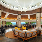 Clérachic LED rope pendants hanging high over a round lounge with wood-framed sofas, seen from further back under a dome.