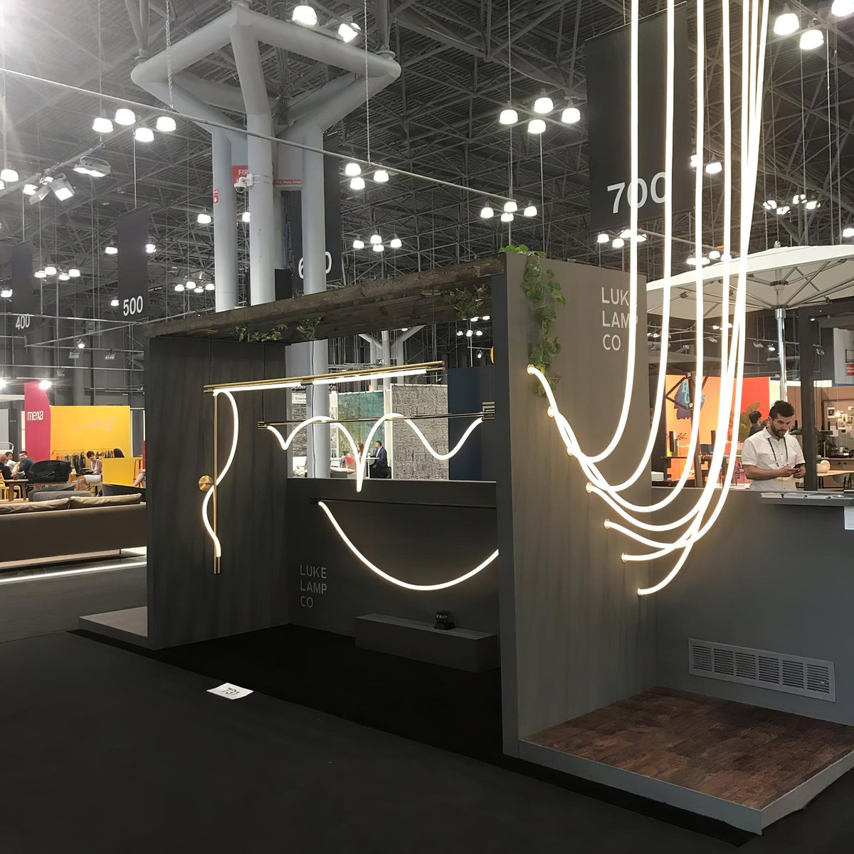 Clérachic LED rope pendants in a trade-show stand, curving in long lines beside a dark display wall with a counter inside.