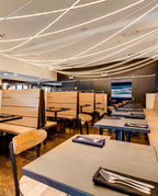 Fine Clérachic LED rope lights criss-crossing the ceiling above wooden booths and tables set with napkins and cutlery.