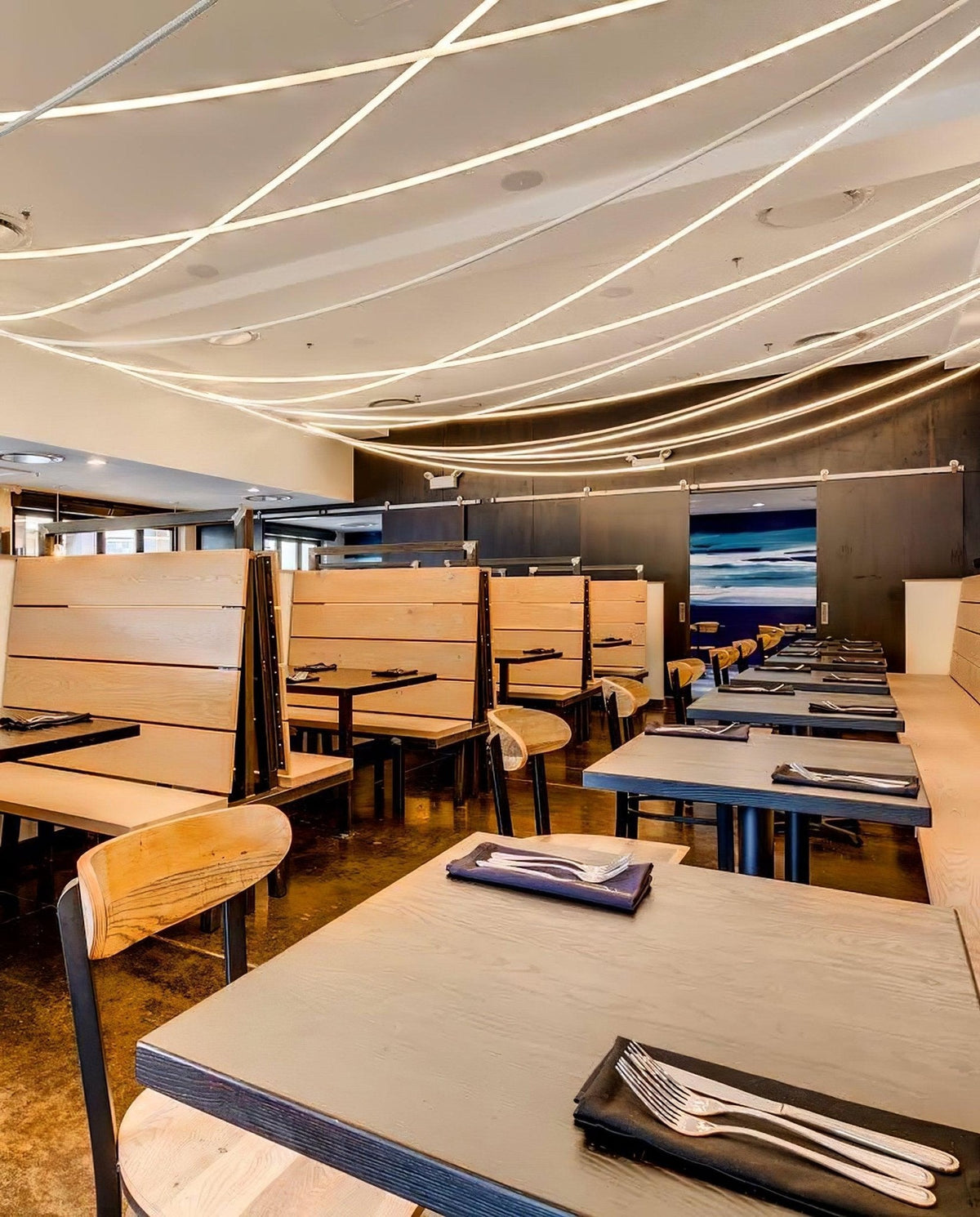 Fine Clérachic LED rope lights criss-crossing the ceiling above wooden booths and tables set with napkins and cutlery.