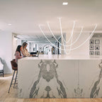 Clérachic LED rope pendants forming deep curves above a long marble-fronted counter where two people work at laptops.