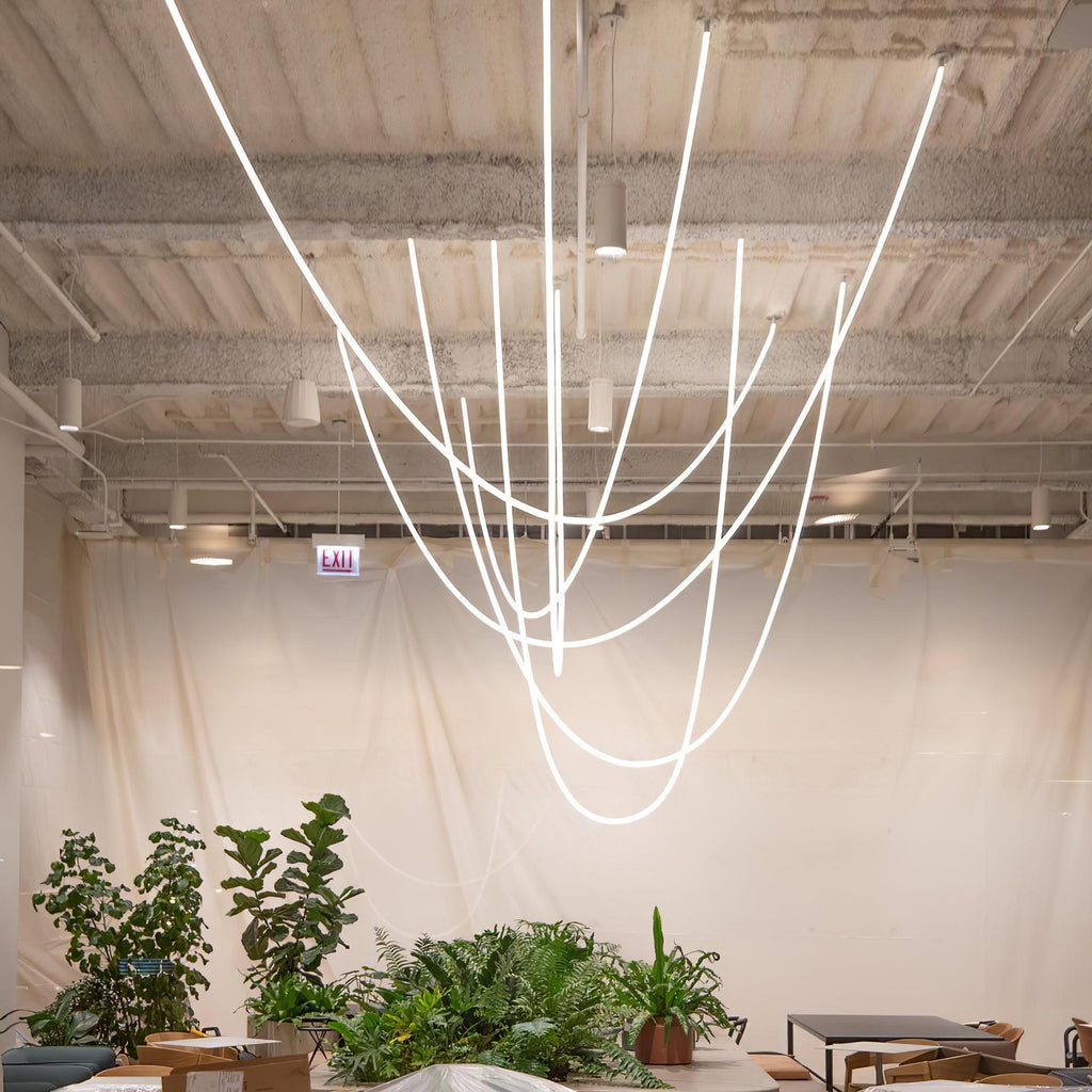 A bunch of Clérachic LED rope pendants forming deep loops above plants and a table, in front of a pale cloth wall.