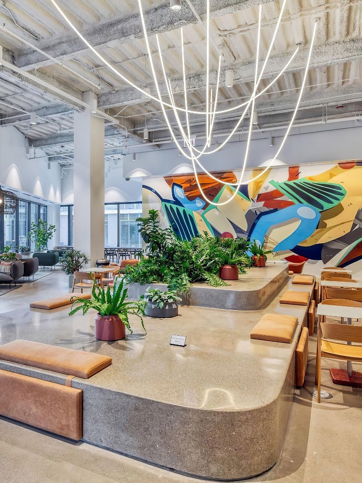 Clérachic LED rope pendants looping across a high ceiling above a long, curved stone bench with plants and mural wall behind.