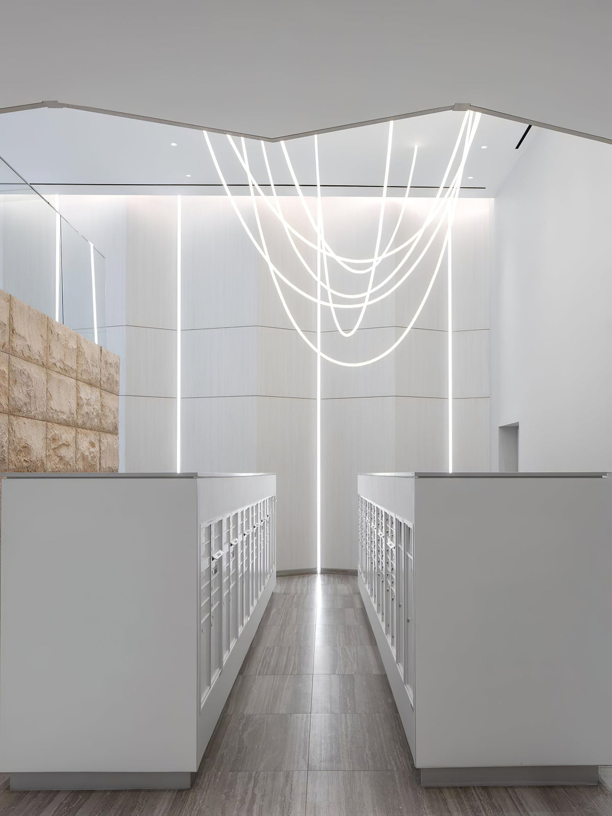 Clérachic LED rope pendants descending in loops through a tall white room with long white counters and soft light strips on the walls.