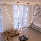 Looking down on Clérachic LED rope pendants hanging beside floor-to-ceiling sheer curtains, over a taupe sofa and a patterned box.
