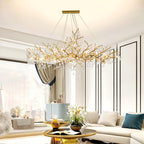 Clérachic Bijou chandelier lit in a bright living room above a cream sofa and a city window.