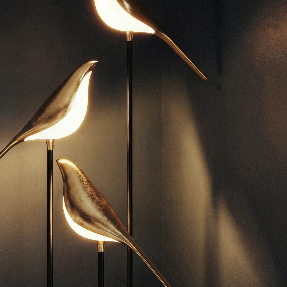 Close view of Clérachic gold-finish bird shades, each with a glowing white underside, on slim black stems
