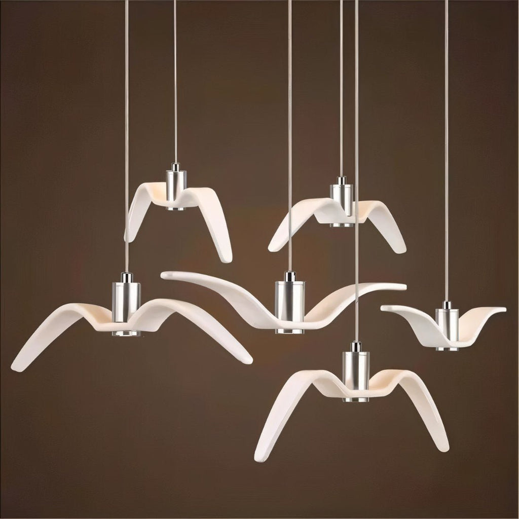 Clérachic six white gull-winged pendants of varied wing shapes on slim cords with aluminium cylinders, against a dark brown ground.
