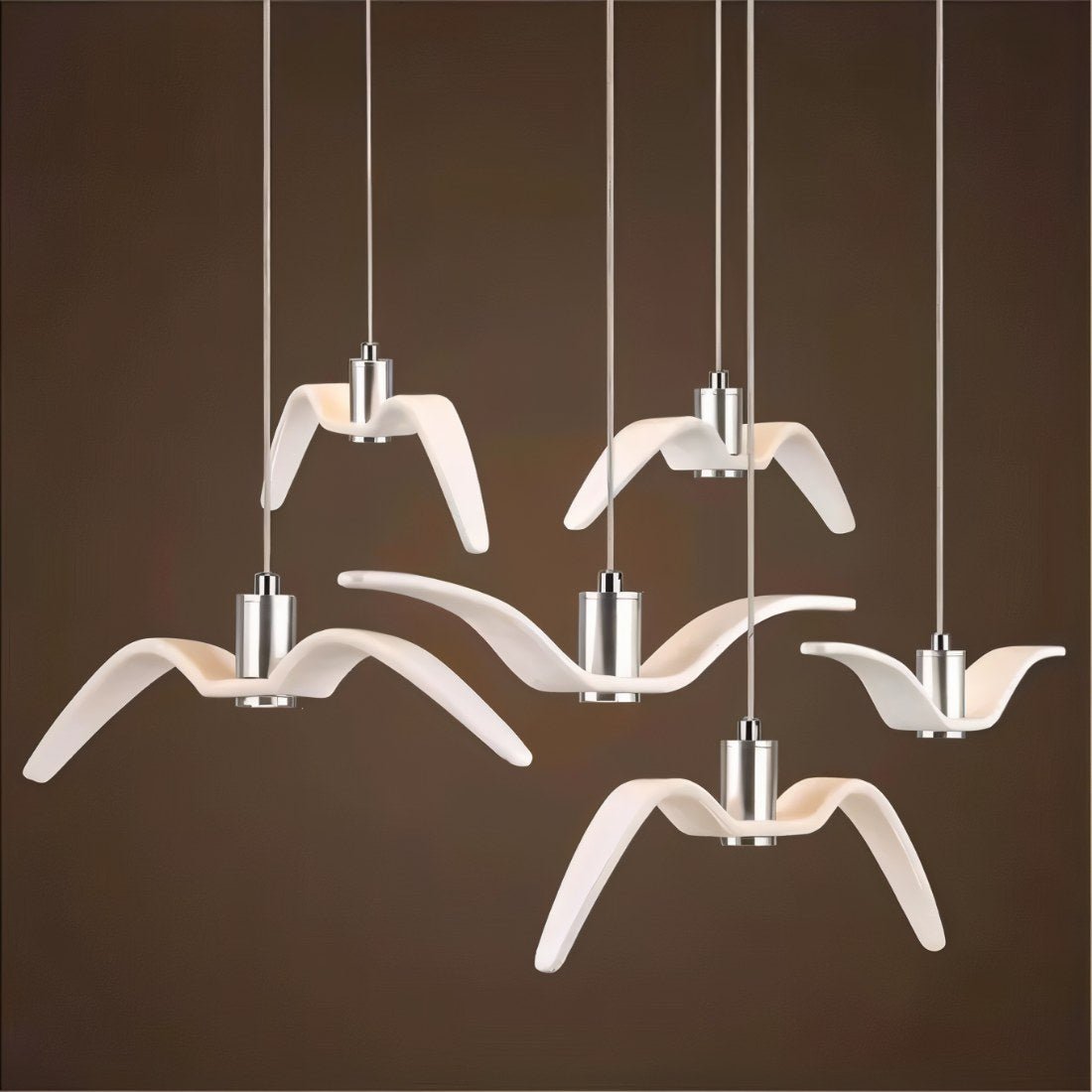 Clérachic six white gull-winged pendants of varied wing shapes on slim cords with aluminium cylinders, against a dark brown ground.