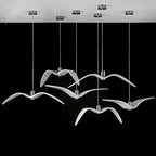 Clérachic six white gull-winged pendants on slim cords from round chrome ceiling plates, seen against a black backdrop.