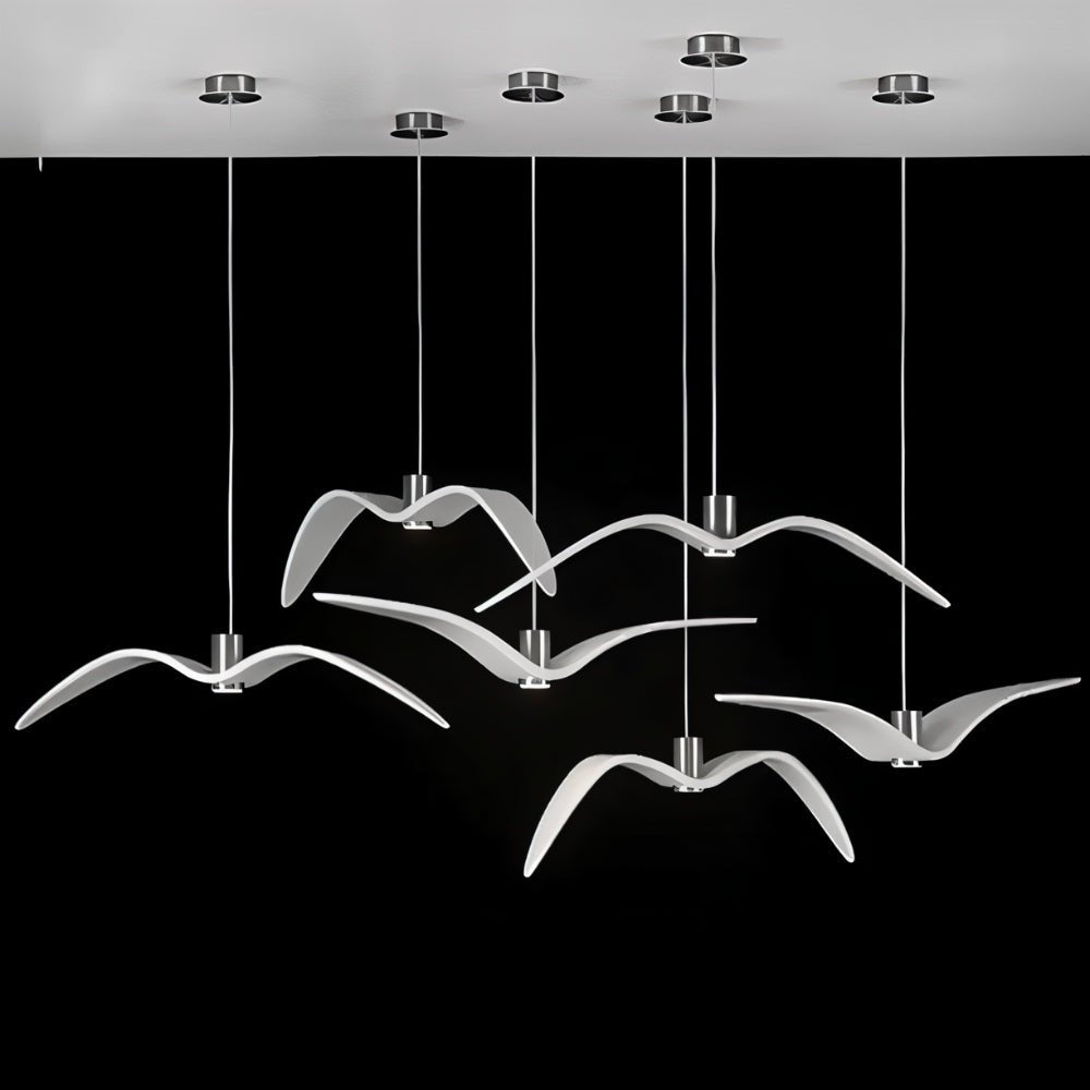 Clérachic six white gull-winged pendants on slim cords from round chrome ceiling plates, seen against a black backdrop.