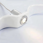 Clérachic close view of a glossy white winged pendant body, its chrome-ringed warm spotlight and aluminium cylinder on a pale ground.