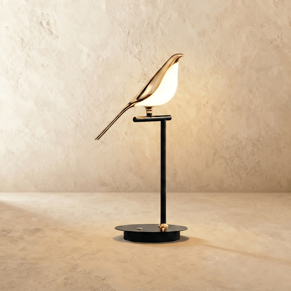 Clérachic one-head bird table lamp with a gold-finish bird and glowing acrylic body on a black stem and round base.