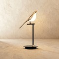 Clérachic one-head bird table lamp with a gold-finish bird and glowing acrylic body on a black stem and round base.