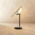 Clérachic one-head bird table lamp with a gold-finish bird and glowing acrylic body on a black stem and round base.