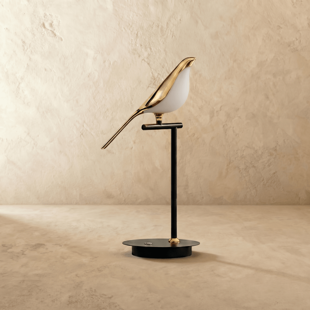 Clérachic one-head bird table lamp switched off, a polished gold bird with a white acrylic belly on a slim black stem.