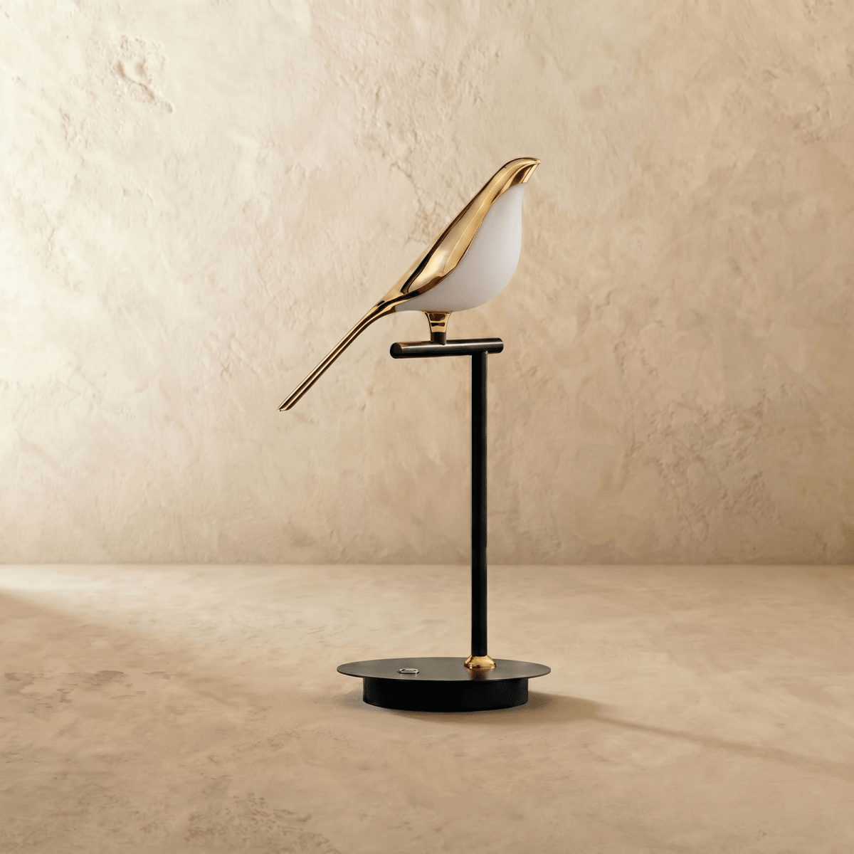 Clérachic one-head bird table lamp switched off, a polished gold bird with a white acrylic belly on a slim black stem.