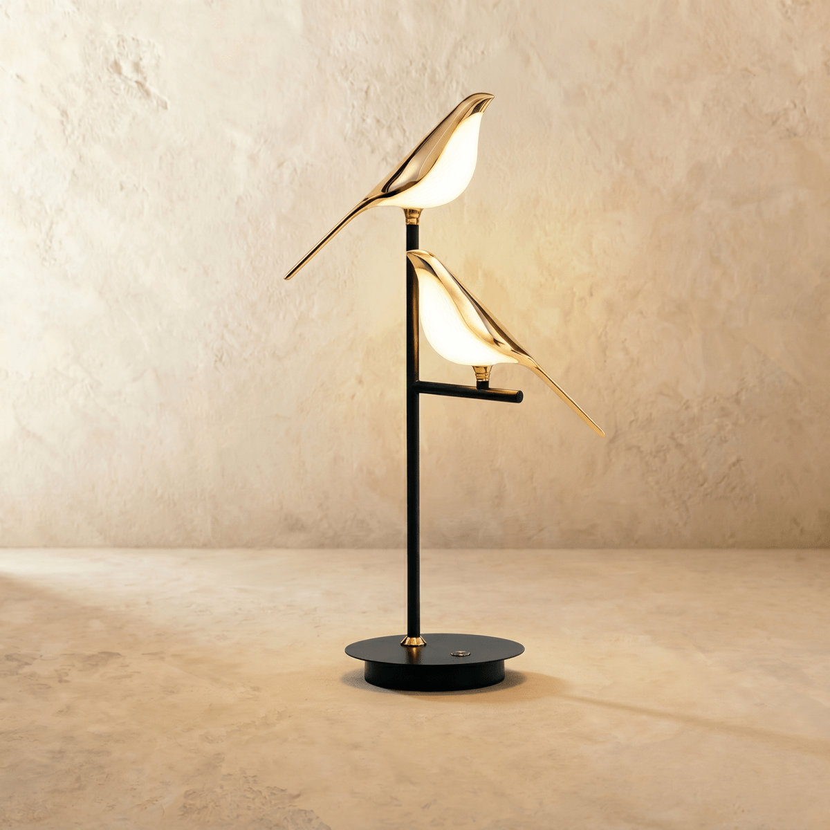 Clérachic two-head bird table lamp with two glowing gold birds perched at different heights on a black stem and round base.