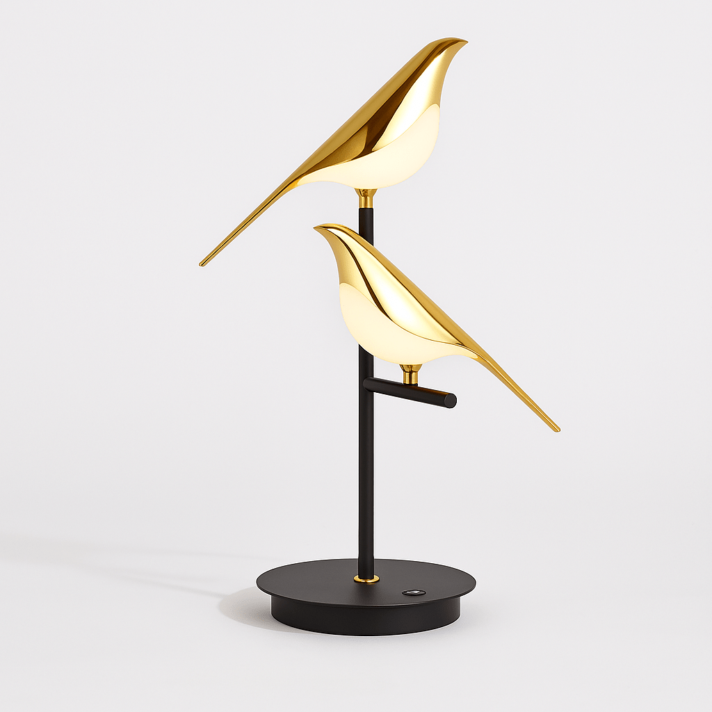 Clérachic two-head bird table lamp on white: two polished gold birds with glowing acrylic bodies on a black stem and disc base.
