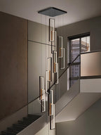 Clérachic black LED frame chandelier of many staggered rectangles with warm inner accents, hung in a stairwell by a window.