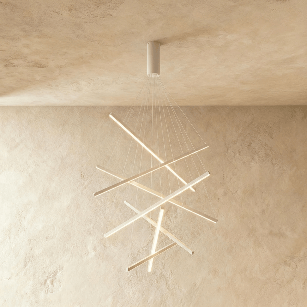 A denser cluster of the Clérachic white staggered chandelier, its aluminium bars glowing warm white against a plaster wall.