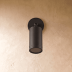 Clérachic black aluminium wall spotlight switched off, showing the matte cylinder, ball joint and dark lens on plaster.