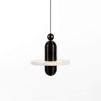 Clérachic single-disc pendant in black hardware, one alabaster plate glowing from the ribbed black capsule on white.