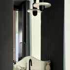 Clérachic single-disc pendants in black reflect in a tall bathroom mirror above a veined marble vanity.
