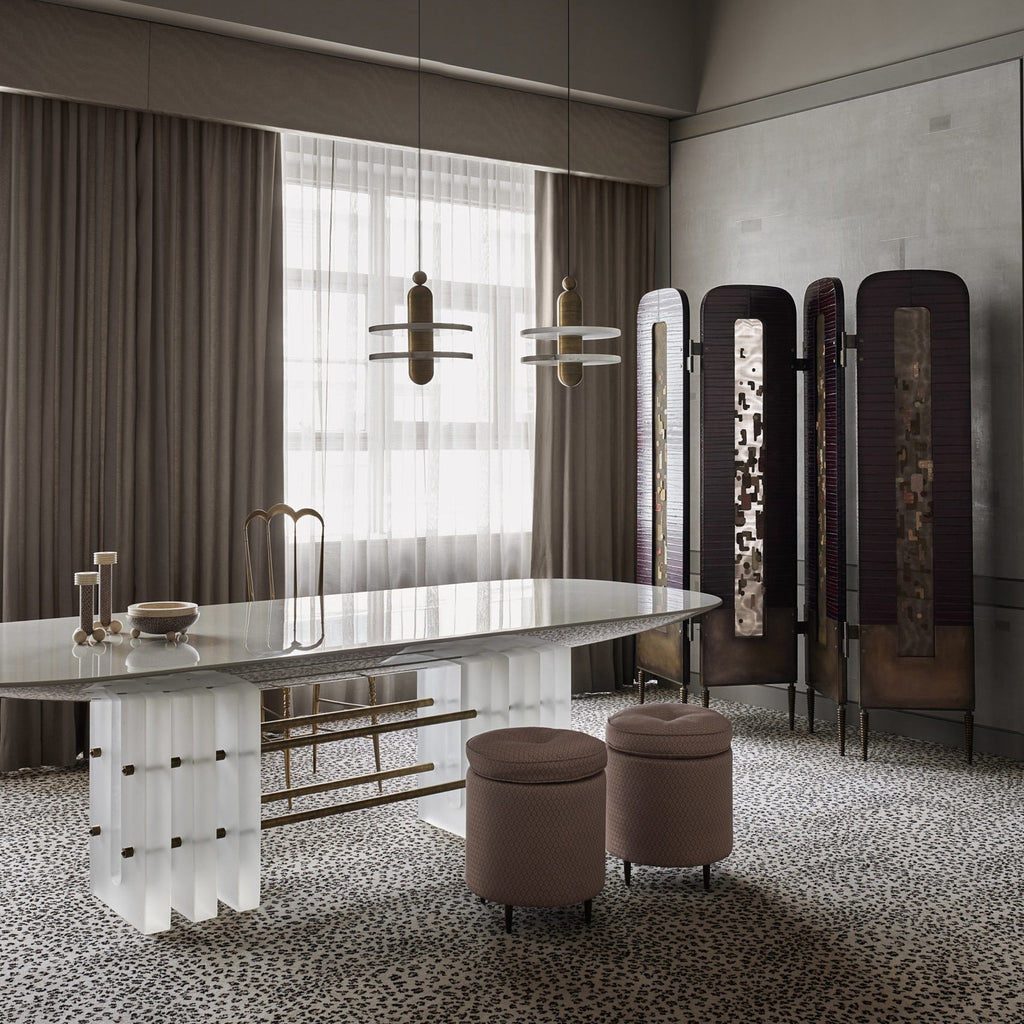 Clérachic double-disc pendants with black-to-gold stems hang over a marble table and mauve ottomans.