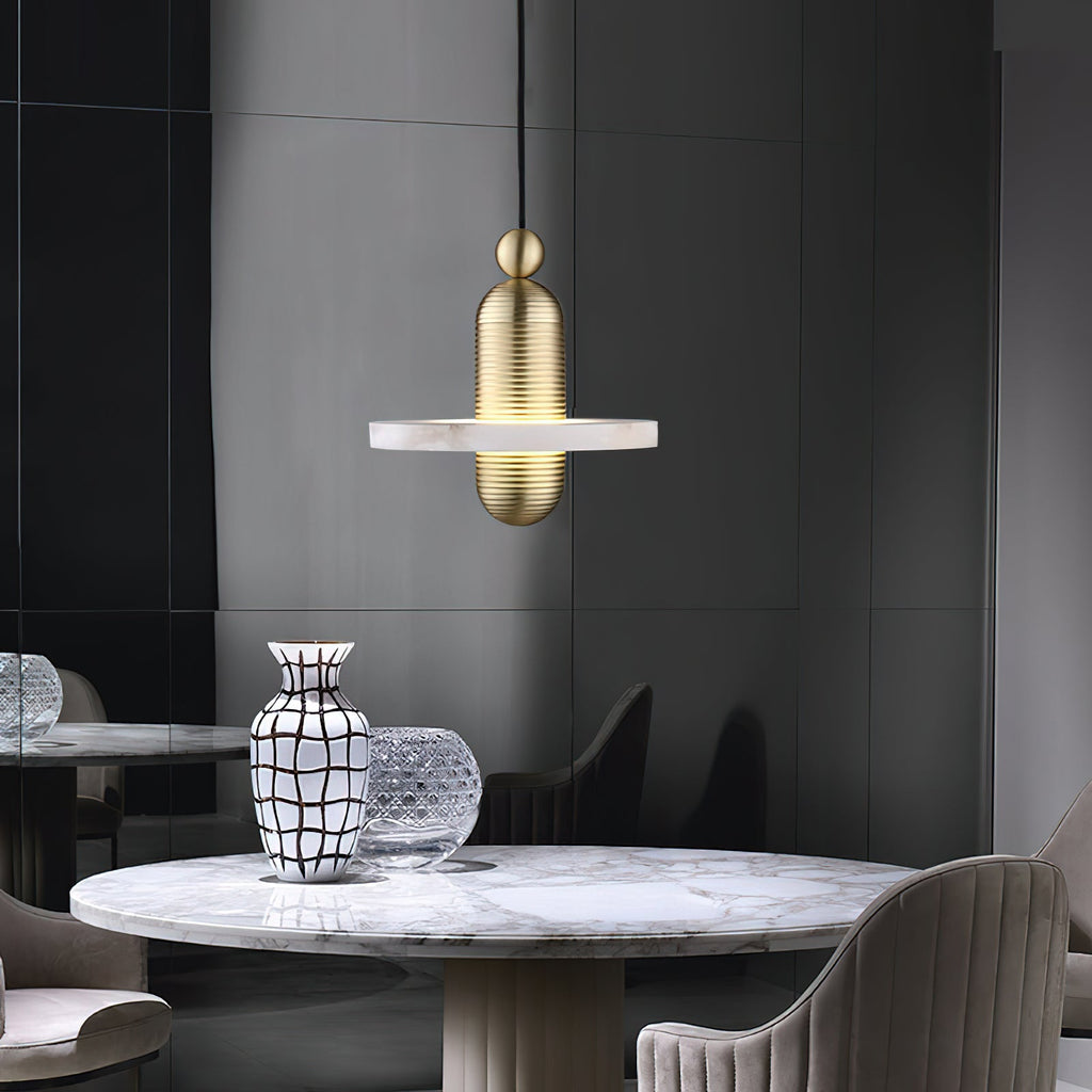 Clérachic gold single-disc pendant hangs over a round marble dining table in a charcoal-paneled room.