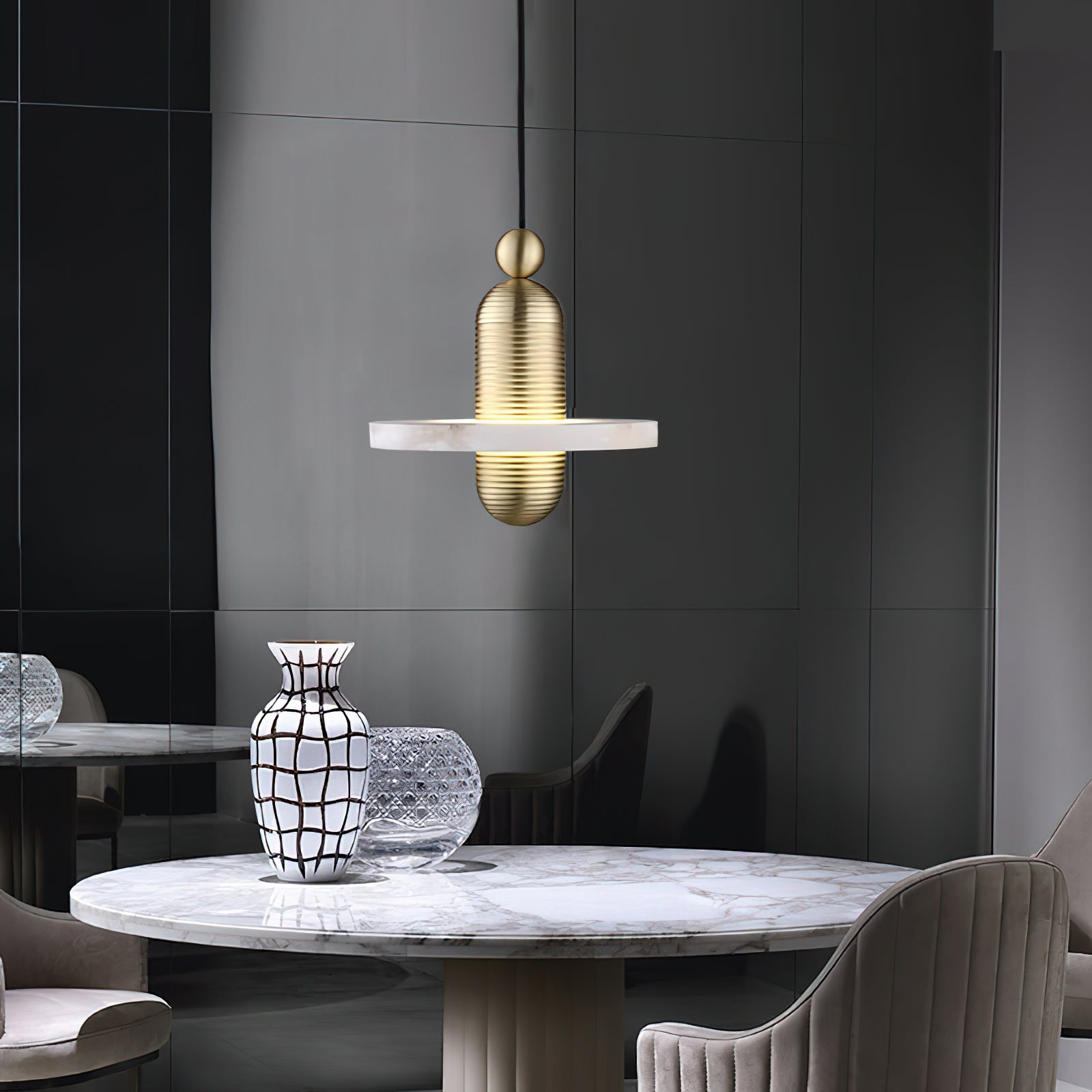 Clérachic gold single-disc pendant hangs over a round marble dining table in a charcoal-paneled room.