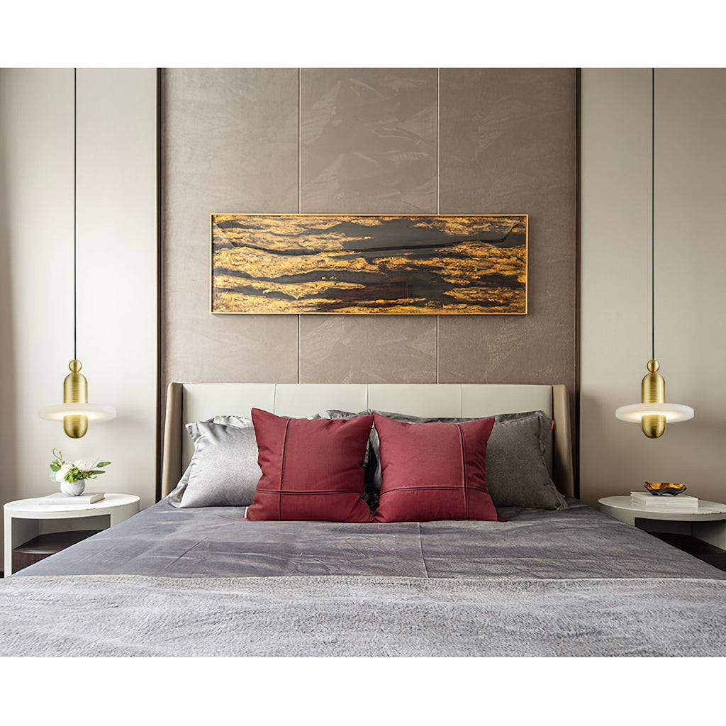 Clérachic gold single-disc pendants flank a beige headboard as bedside lights over small white nightstands.
