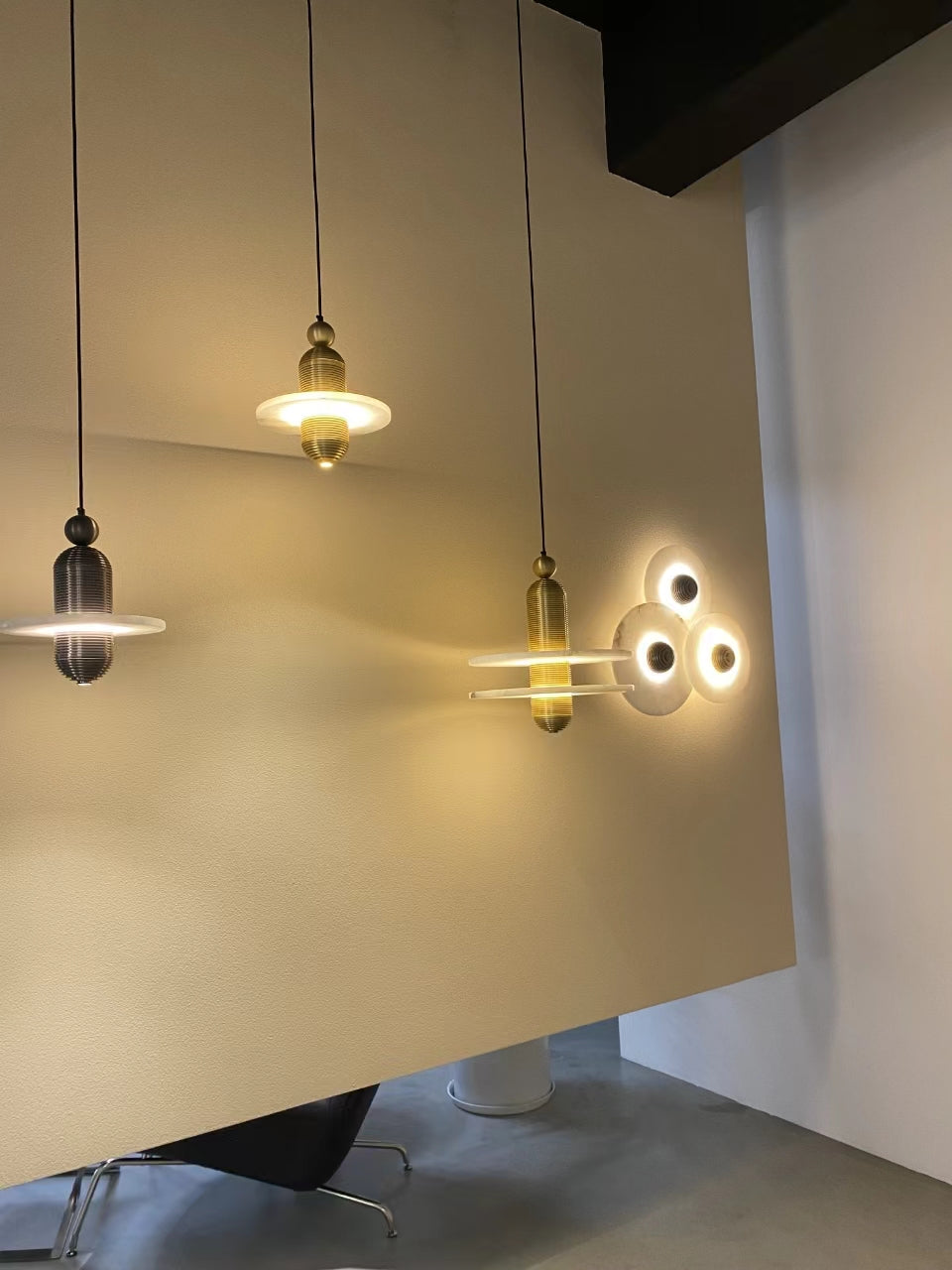 Clérachic pendants compared: black single-disc, gold single-disc, and gold double-disc on a cream wall.