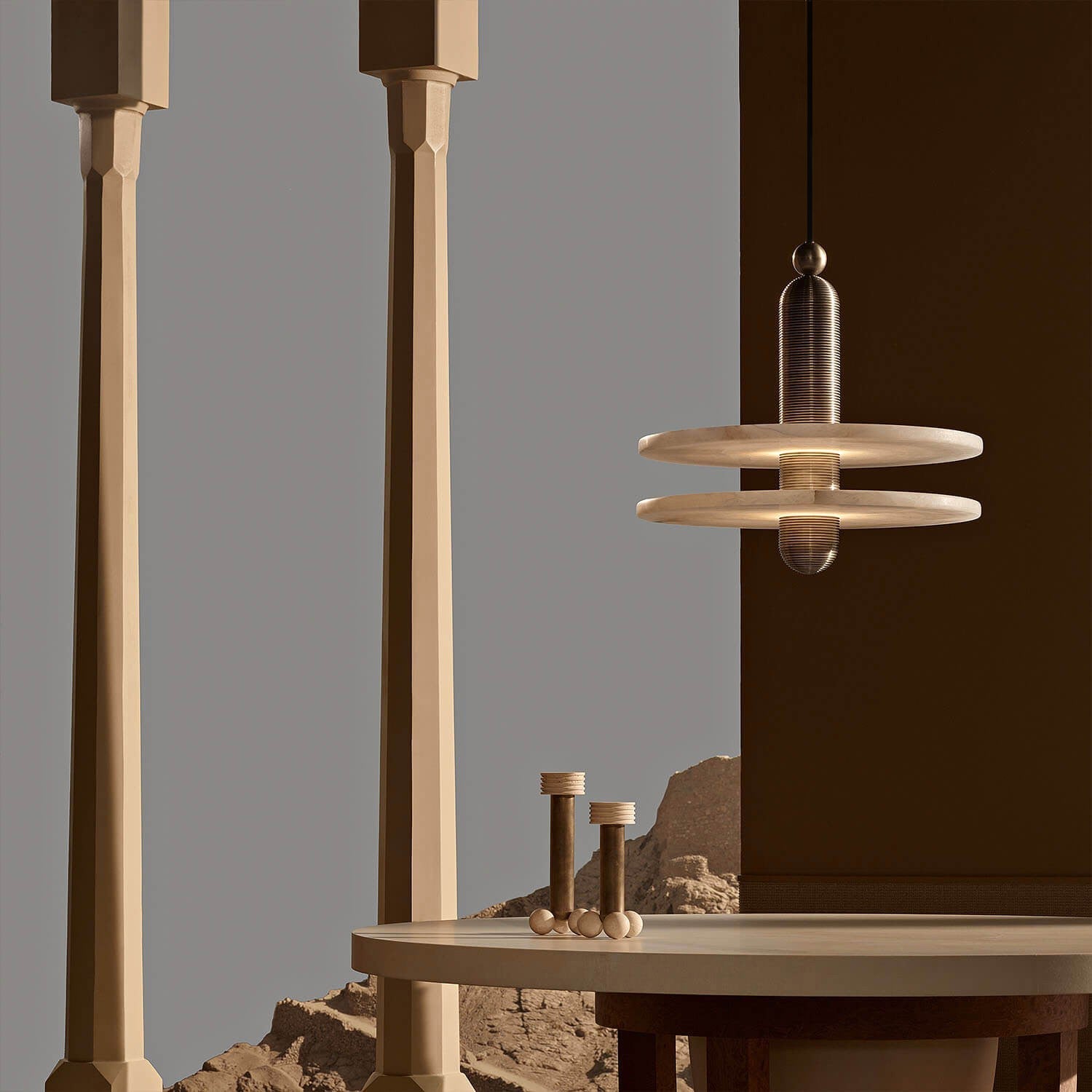 Clérachic black double-disc pendant hangs by tan pillars and a cream table opening onto rocky ground.