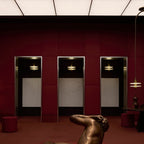 Clérachic gold double-disc pendants hang in red-paneled alcoves above a bronze reclining figure.