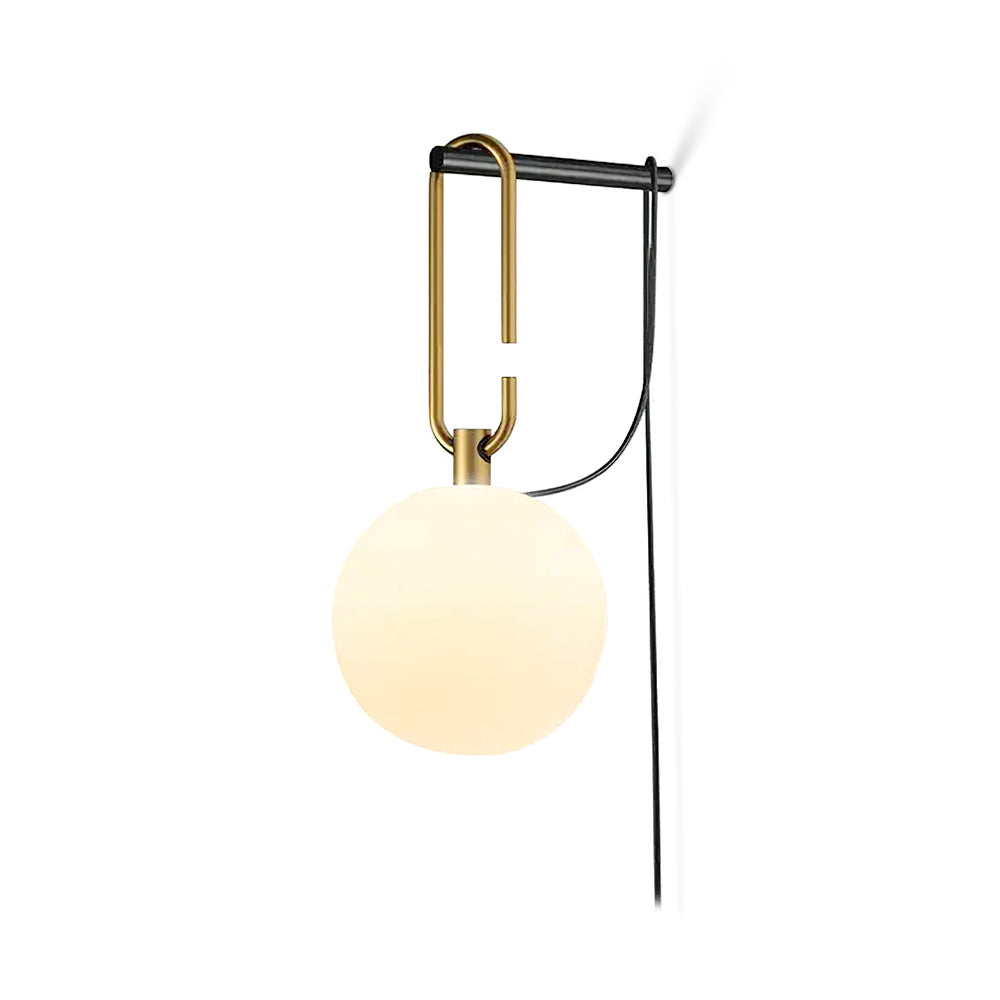 A Clérachic globe wall lamp glowing warm cream on a plain white background, its black cord running down beside it.