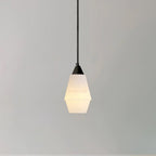 Studio shot of the lit Clérachic Black and White Alabaster Pendant Light, angular double-cone shade glowing on grey.