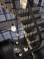 Clérachic Black and White Alabaster Pendant Lights drop through a stairwell, black treads and a curved rail around the glow.