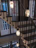 Clérachic Black and White Alabaster Pendant Lights line a stone stair, city windows and brick facades beyond the void.