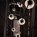 Clérachic Black and White Alabaster Pendant Lights fall in a warm column down a dark stairwell, black cords in shadow.