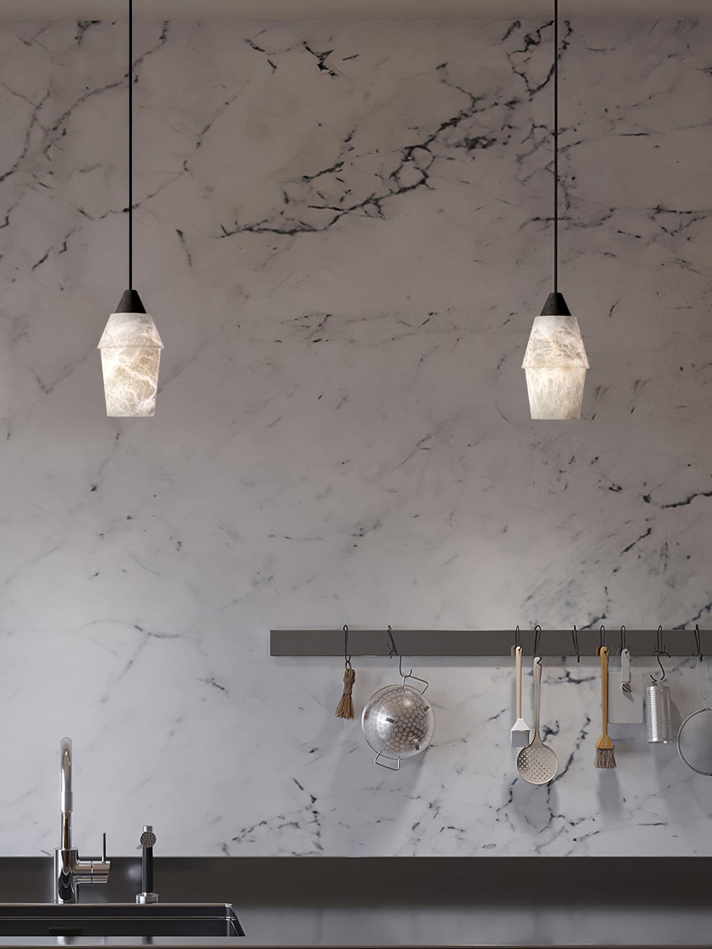 Two Clérachic Black and White Alabaster Pendant Lights hang over a marble kitchen wall with a black counter and faucet.