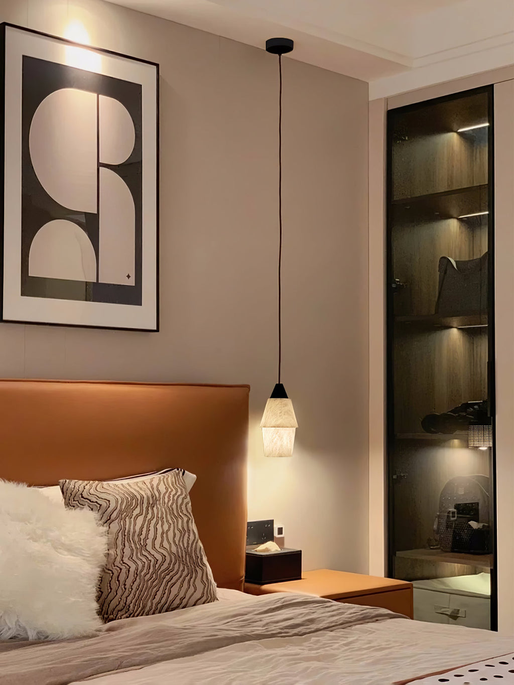 Clérachic Black and White Alabaster Pendant Light hangs low over a wood nightstand in a bedroom with framed abstract art.