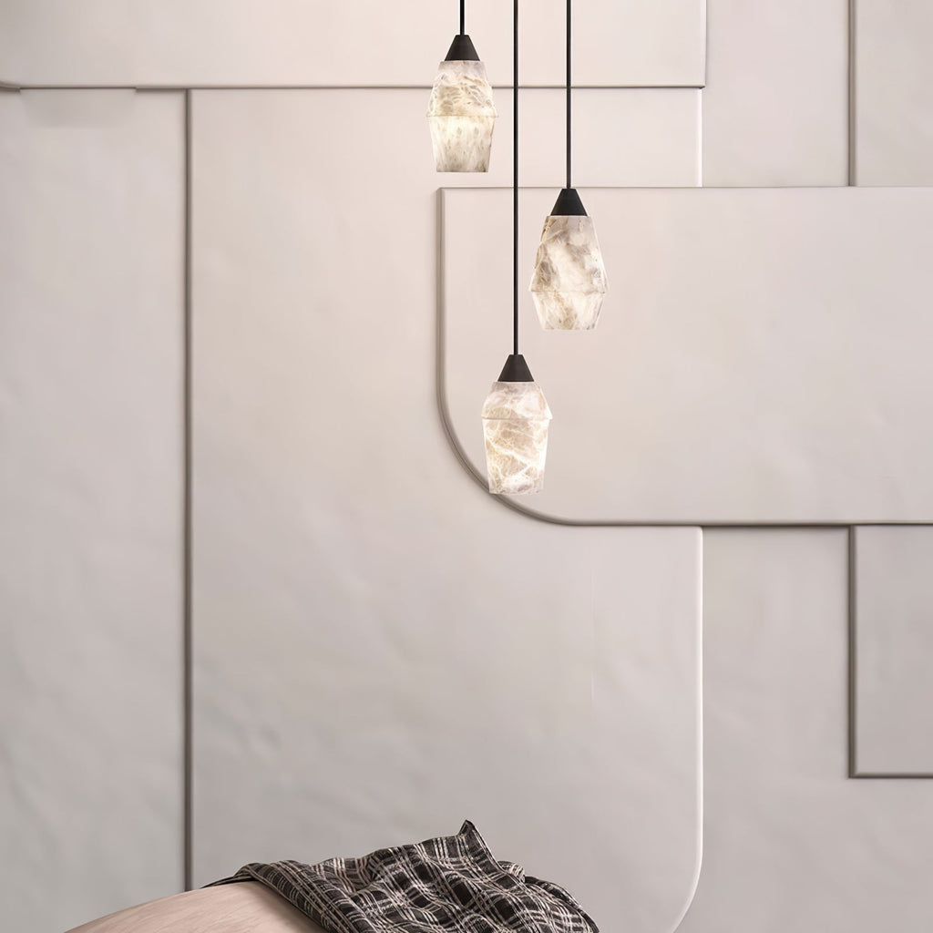 Three Clérachic Black and White Alabaster Pendant Lights hang at staggered heights before cream geometric wall panels.