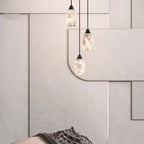 Three Clérachic Black and White Alabaster Pendant Lights hang at staggered heights before cream geometric wall panels.
