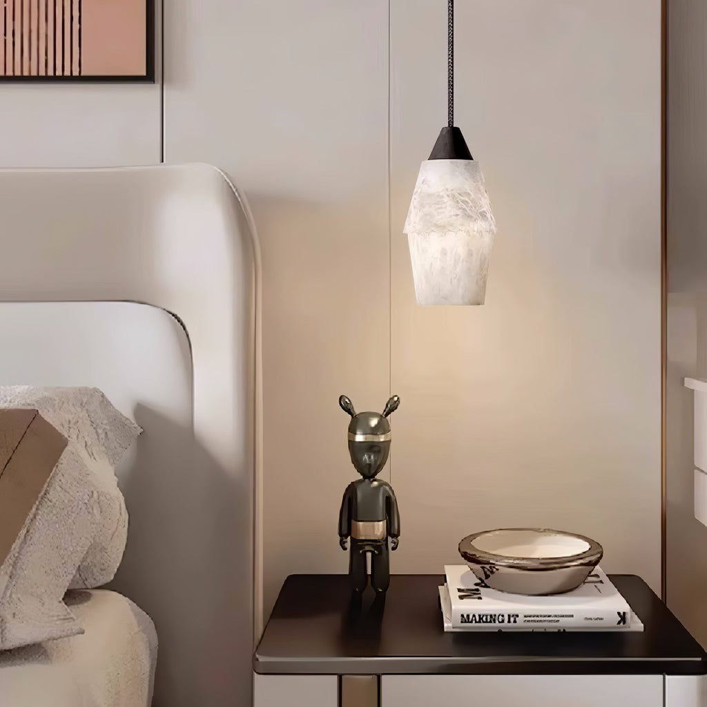 Clérachic Black and White Alabaster Pendant Light lights a dark nightstand stacked with books, a figurine, and a shallow bowl.
